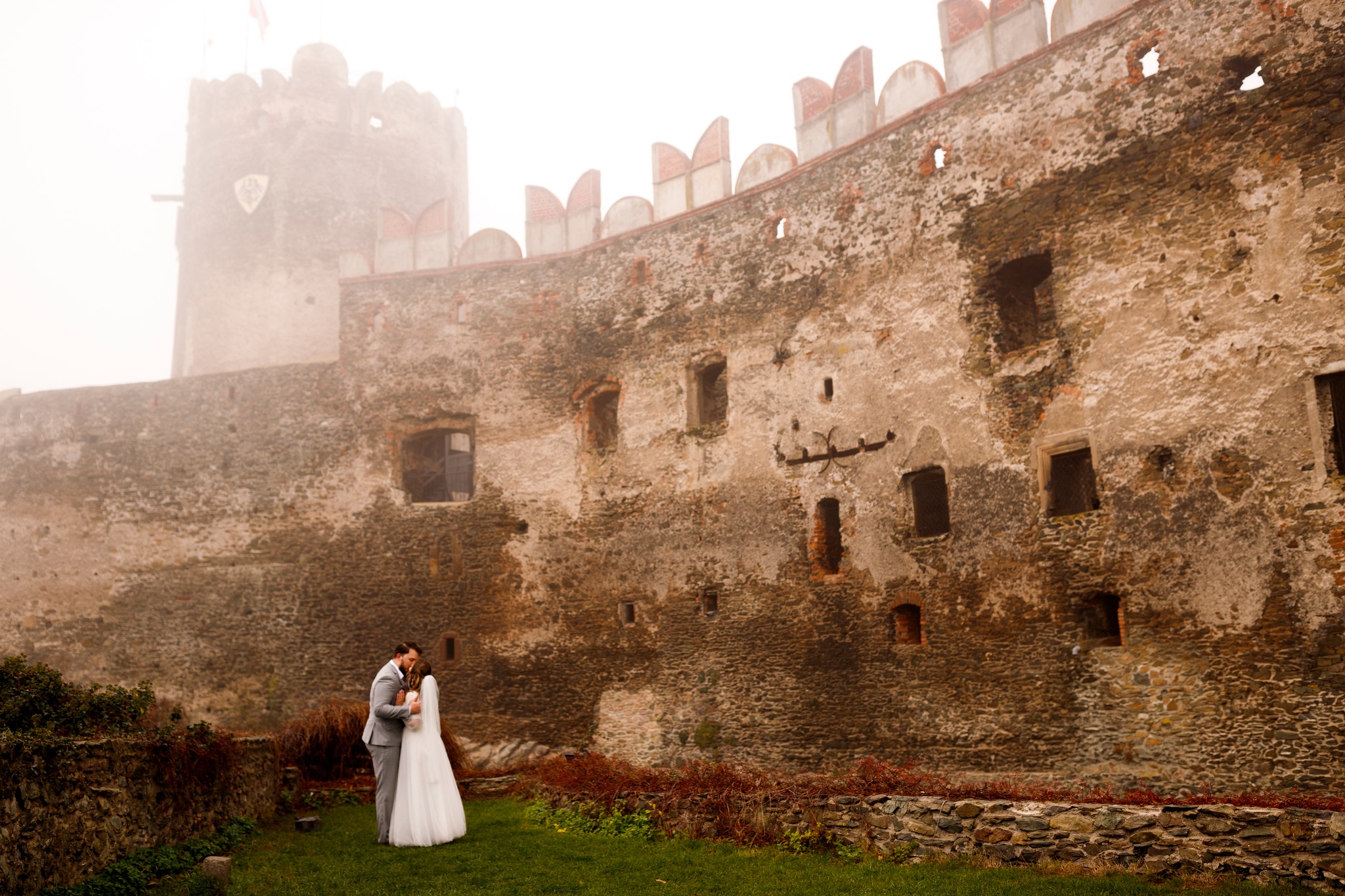 Romantyczna chwila podczas sesji ślubnej – para młoda na tle zamku we mgle