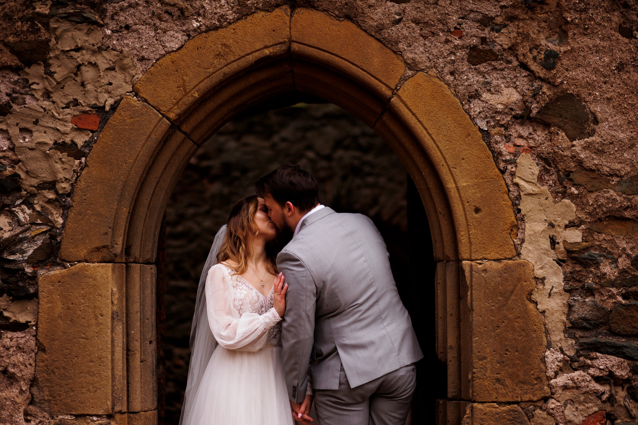 Romantyczna chwila podczas sesji ślubnej – para młoda stoi w drzwiach ze stylizowana, kamienną futryną