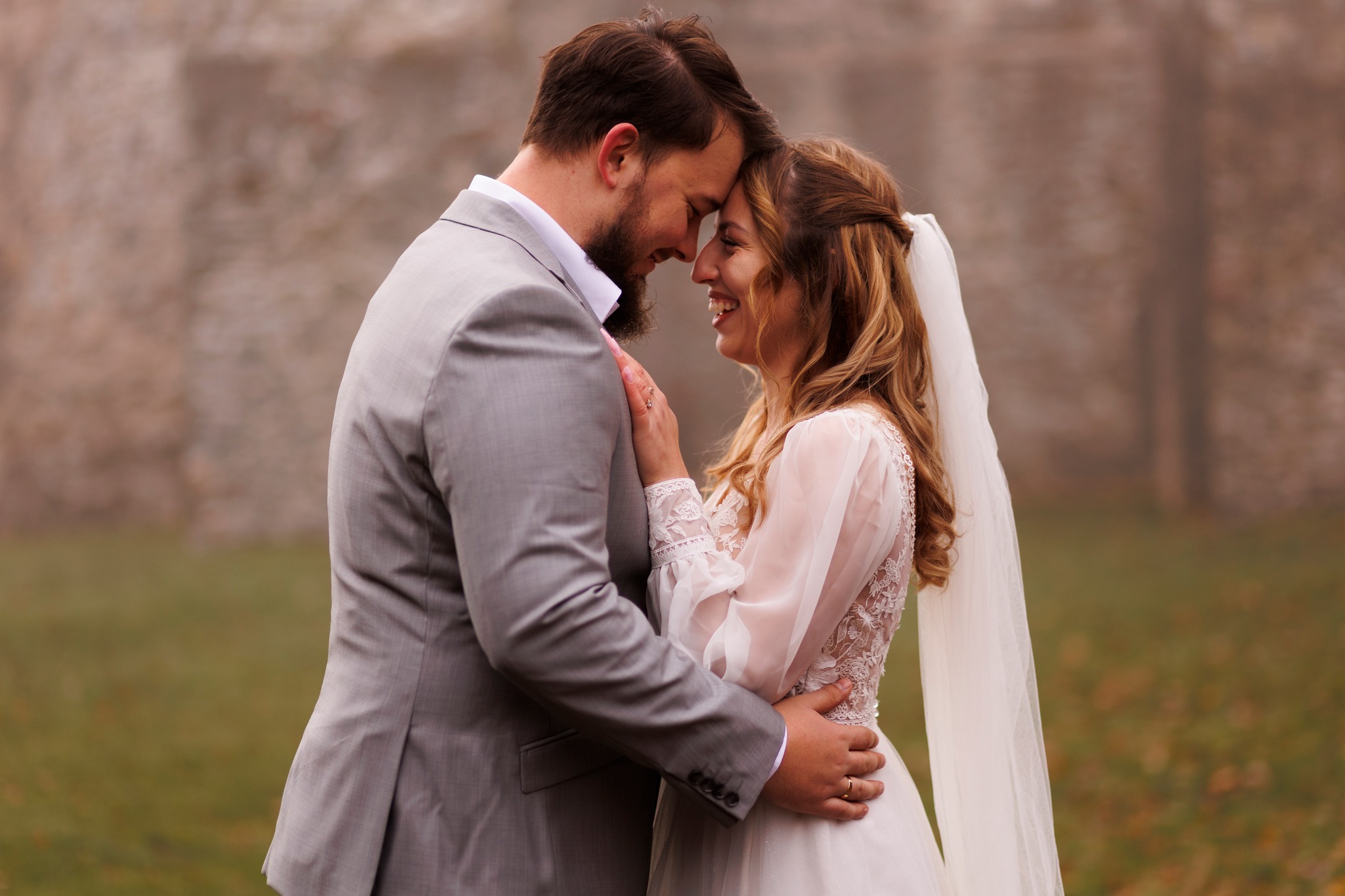 Romantyczna chwila podczas sesji ślubnej – para młoda na tle ściany zamkowej