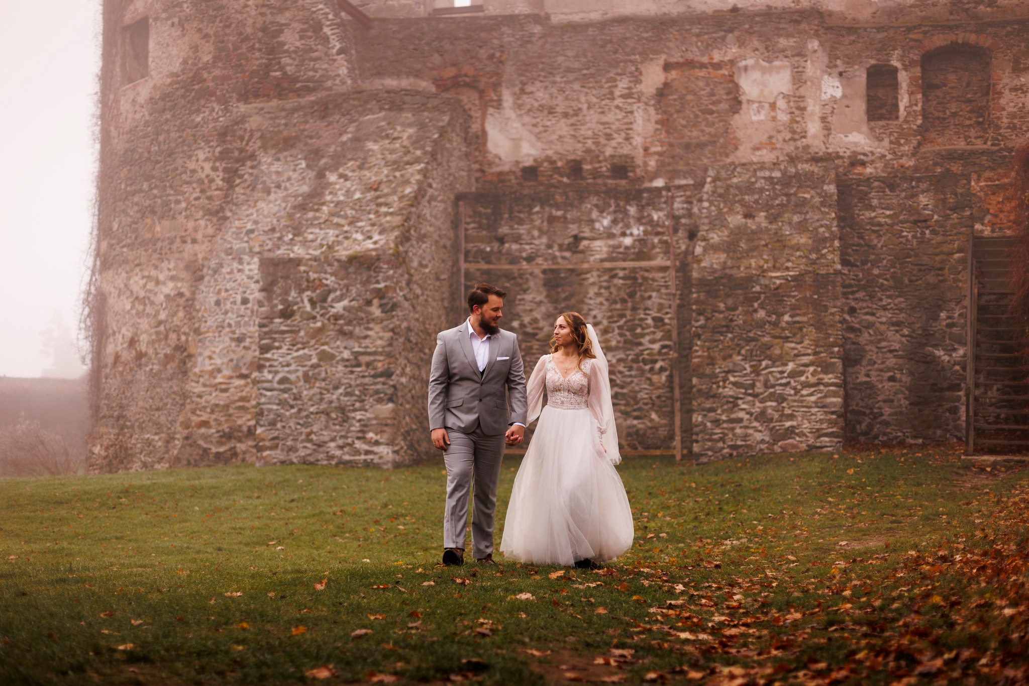 Romantyczna chwila podczas sesji ślubnej – para młoda na tle ściany zamkowej