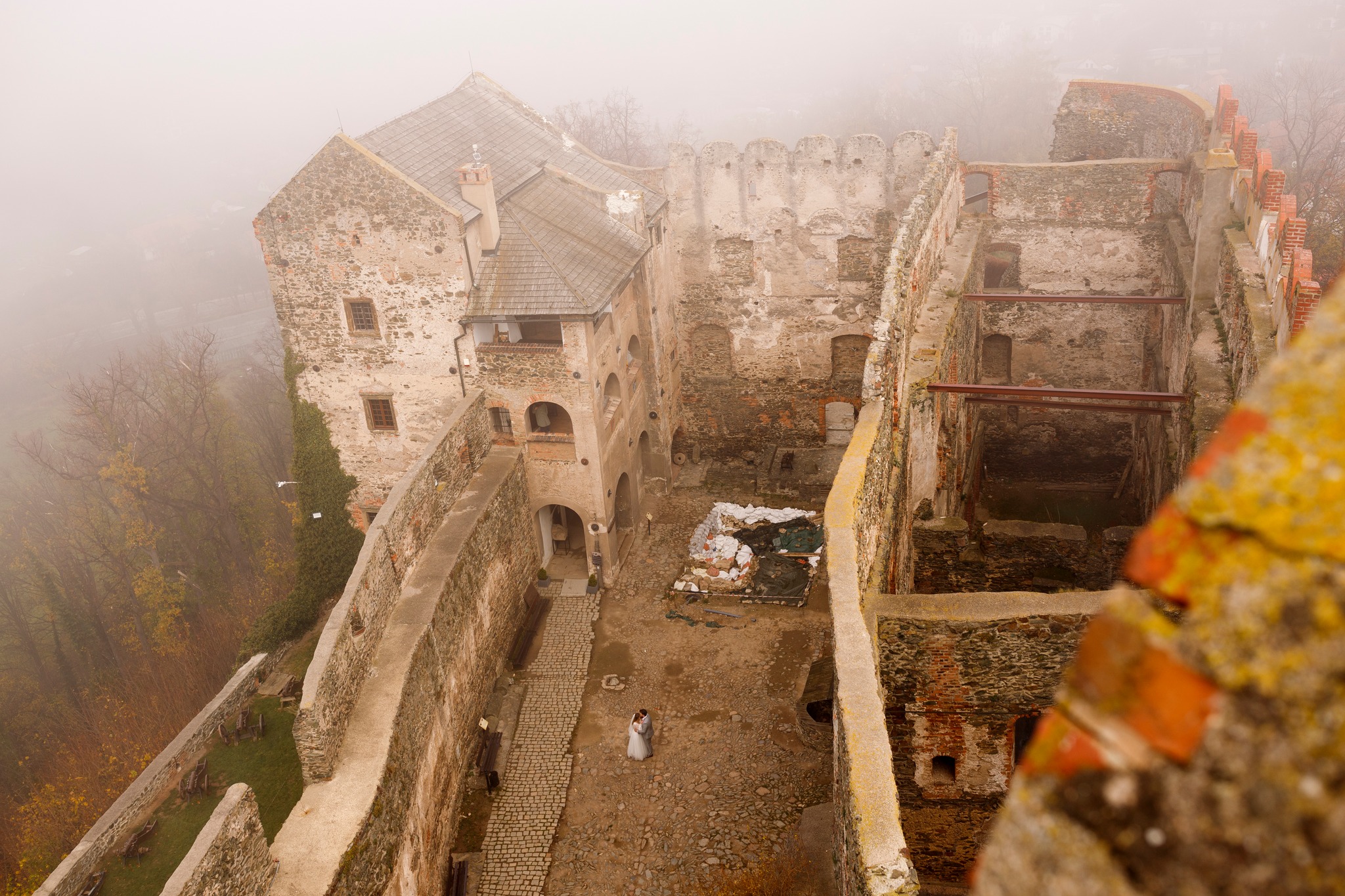 Romantyczna chwila podczas sesji ślubnej – para młoda na dziedzińcu zamku widoczna z wierzy