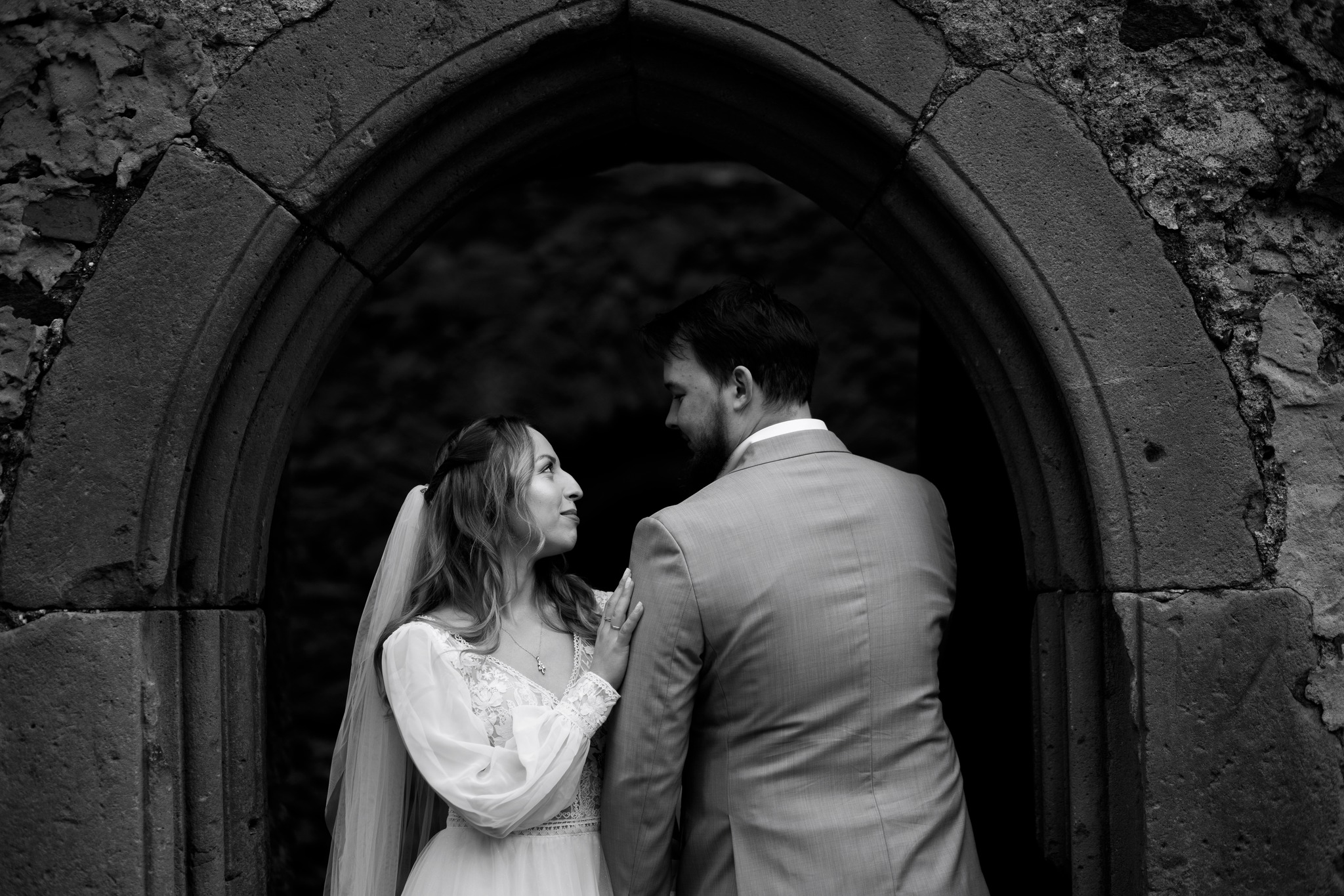 Romantyczna chwila podczas sesji ślubnej – para młoda stoi w drzwiach ze stylizowana, kamienną futryną